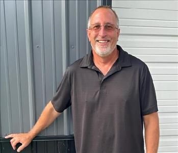 Male employee in dark shirt standing in front of gray and white walls