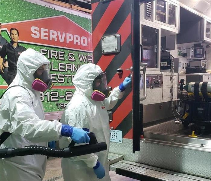 SERVPRO employees in full hazmat gear helping to clean a fire engine 